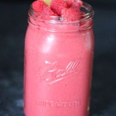 a pink smoothie is in a mason jar