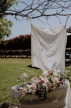 a basket filled with flowers sitting on top of a grass covered field next to a tree