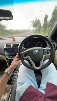 a person sitting in the driver's seat of a car with their hands on the steering wheel