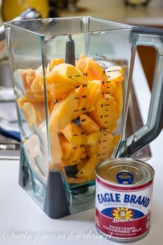 a blender filled with lots of fruit next to a can