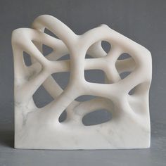 a white sculpture sitting on top of a table next to a gray wall and floor