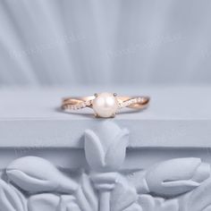 a close up of a ring on top of a white box with flowers and leaves