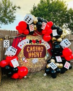 a casino themed party with balloons, dices and streamers on the grass in front of a fence