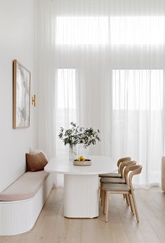 a white dining room table with four chairs and a bench in front of the window