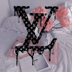 the letter v is made up of letters and flowers in front of a book on a bed