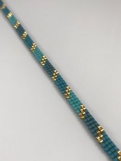 a blue and gold beaded bracelet on a white surface