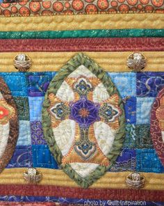 a close up view of a quilted wall hanging with decorative designs on the edges