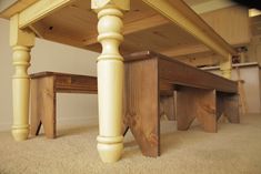 a table with two benches underneath it on carpeted flooring in front of white walls