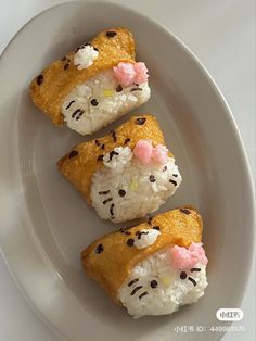 three sushi rolls with rice and cat's face on them sitting on a white plate