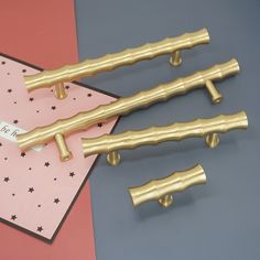 three golden metal handles on top of a pink and gray table next to a card