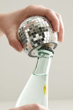 a person holding a bottle with a disco ball on top of it and another hand reaching for the bottle