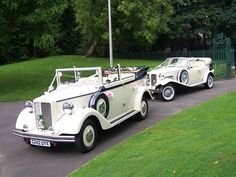 two antique cars parked on the side of a road