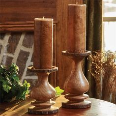 two wooden candlesticks sitting on top of a table next to a planter