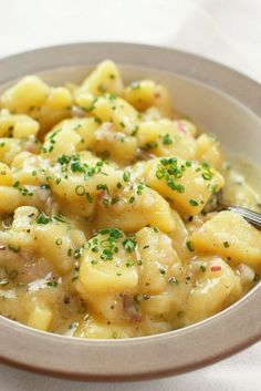 a bowl filled with macaroni and cheese covered in parsley on top of a white table cloth