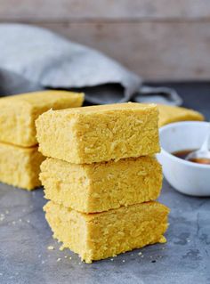 three squares of cornbread next to a bowl of dipping sauce