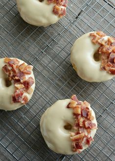 four doughnuts with bacon on them sitting on a cooling rack, ready to be eaten