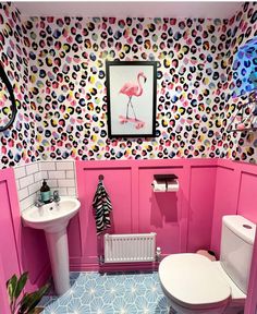 a bathroom decorated in pink, blue and white with an animal print wallpaper on the walls