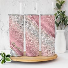 three pink glitter tumblers sitting on top of a wooden tray next to a plant