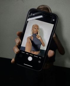 a person holding up a cell phone with an image of a woman on the screen