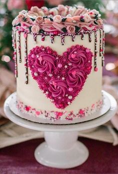 a white cake with pink frosting and flowers in the shape of a heart on top