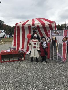 two children dressed up as clowns standing in front of a circus tent with red and white striped walls