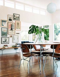 a dining room table with chairs and a vase filled with plants on top of it