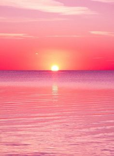 the sun is setting over the ocean with pink and purple hues in the sky