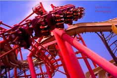 the roller coaster at an amusement park is red and yellow with purple trimmings