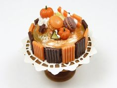 there is a small cake on top of a doily with pumpkins and other decorations