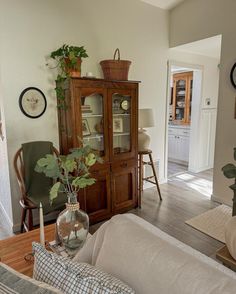 a living room filled with furniture next to a wooden table and wall mounted clock on the wall