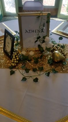 the table is decorated with gold and white flowers, greenery, and other decorations