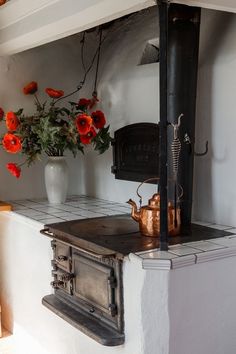 a stove top oven sitting inside of a kitchen next to a vase filled with flowers