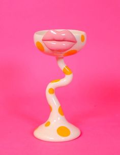 a pink and yellow polka dot vase on a pink background