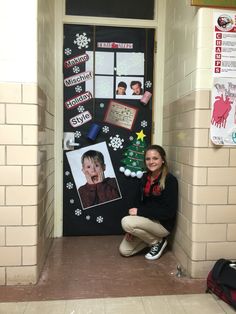 a woman kneeling down in front of a door decorated with pictures and snowflakes