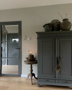 a living room with an armoire, table and vases on top of it