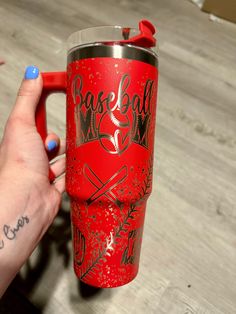 a person holding a red coffee cup with baseball on it and the word base ball painted on it