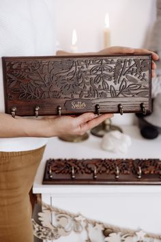 a person holding a wooden box with two candles in it and another candle holder behind them