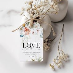 a tag that says love is in the air next to some dried flowers and eggs