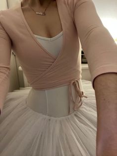 a woman wearing a pink top and white tulle skirt is taking a selfie