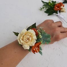 two wrist corsages with orange and white flowers