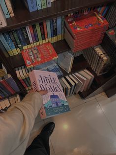 a person holding up a book in front of a bookshelf full of books