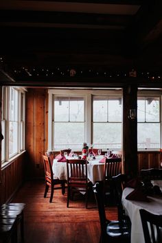 a dining room with tables and chairs in front of two large windows that look out onto the outdoors