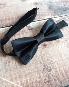 "This pre-tied men's bowtie comes in a simple and classic style. With it's slim batwing shape you can choose from a variety of colours. The matching embroidered initials add a subtle and personal twist, these are made in a matching thread colour featured on the front bottom right corner of the bow. DETAILS: This bowtie is approx. 5\" by 2.5\" and fastens with an adjustable strap fitting up to a max neck width of 18 inches with a hook and eye closure. We can make wider widths upon request. Max 3 Classic Bow Tie For Black-tie Events, Classic Adjustable Bow Tie For Black-tie Events, Adjustable Black Bow Tie For Father's Day, Adjustable Bow Tie For Black Tie Events, Dapper Bow Tie For Formal Father's Day, Adjustable Bow Tie For Black-tie Events, Dapper Adjustable Bow For Black Tie Events, Adjustable Dapper Bow For Black Tie Events, Fitted Bow Tie As A Gift