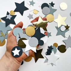 a hand is holding some paper stars and confetti