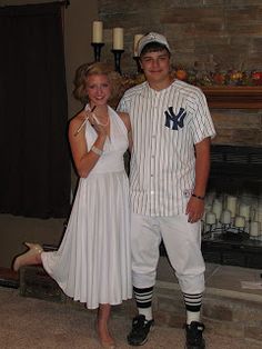 a man and woman dressed in baseball uniforms posing for a photo with candles on the fireplace