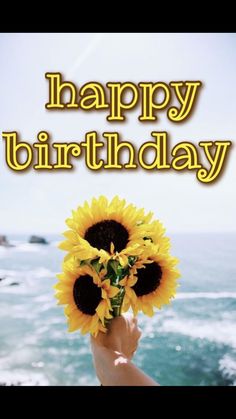 a person holding up a sunflower with the words happy birthday written in yellow on it