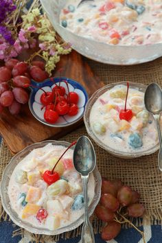 two bowls filled with fruit on top of a table next to grapes and cherries