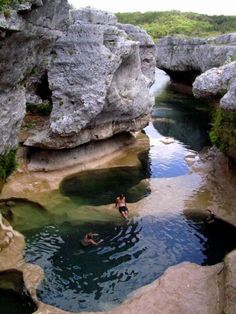 two people swimming in a river surrounded by rocks