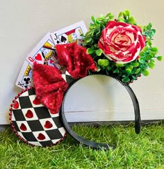 a minnie mouse ears headband with flowers and playing cards on the grass in front of a wall