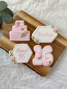 three decorated birthday cakes sitting on top of a wooden cutting board next to a potted plant